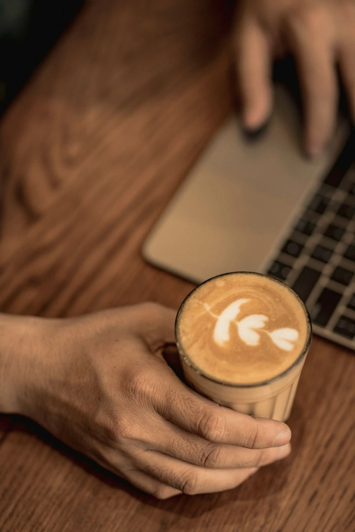 person holding white ceramic cup with cappuccino